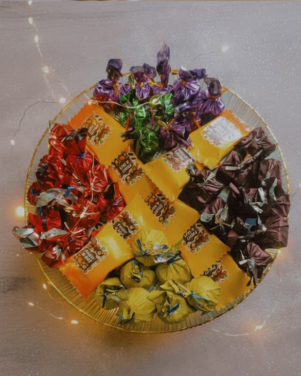 Assorted colorful candies in a decorative box on a light surface.